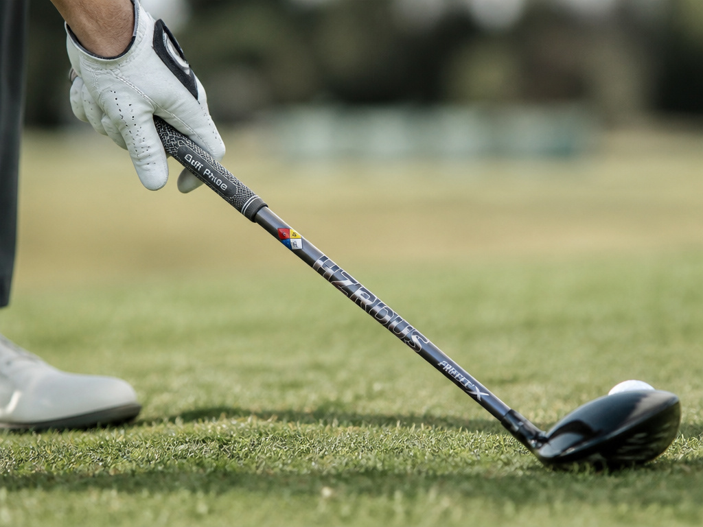 Golfer's hands gripping a driver, highlighting grip, shaft, and tee setup for optimal driving.